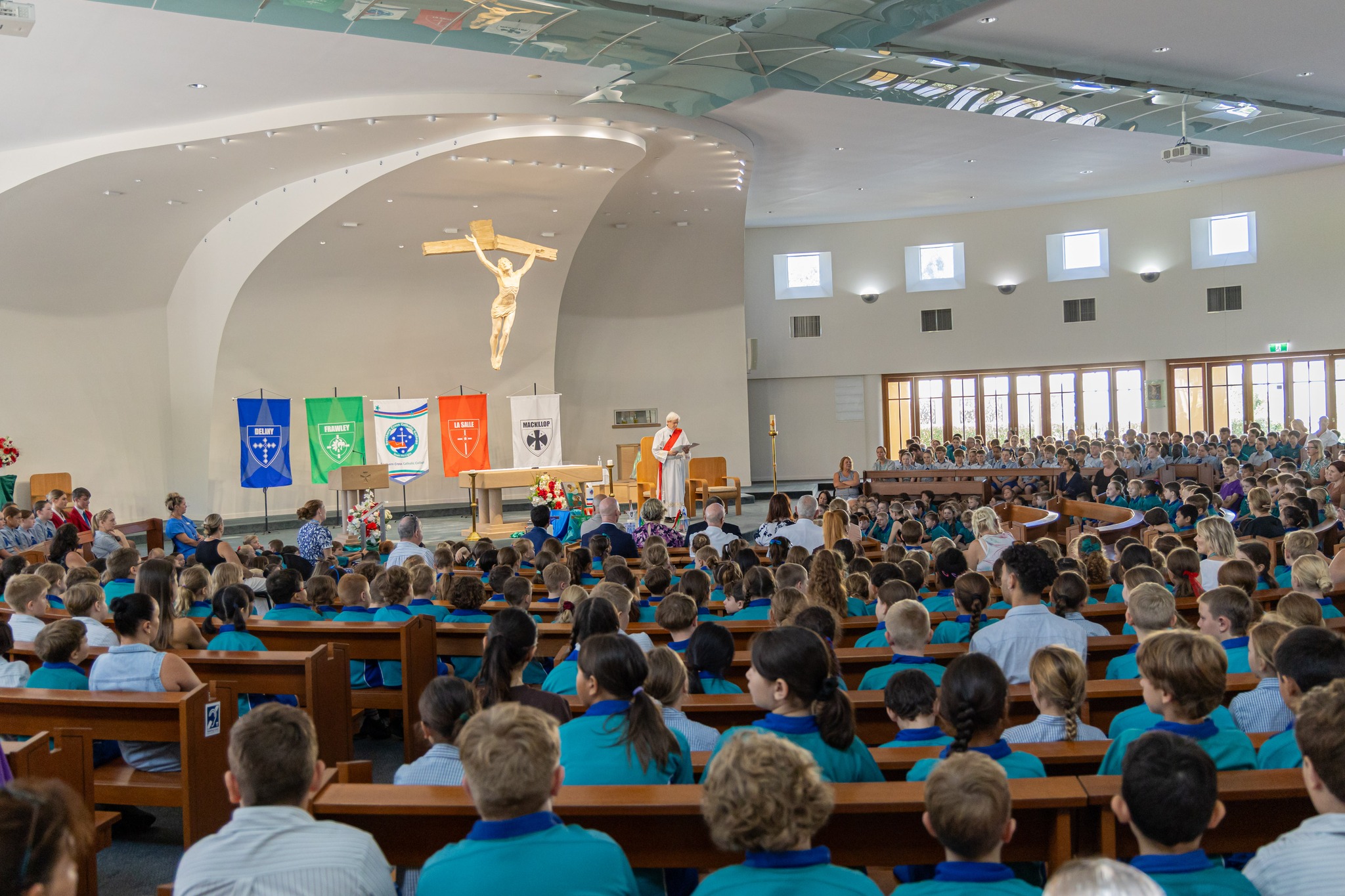Photo taken from rear of church showing many students and staff in congregation with parish priest standing on altar