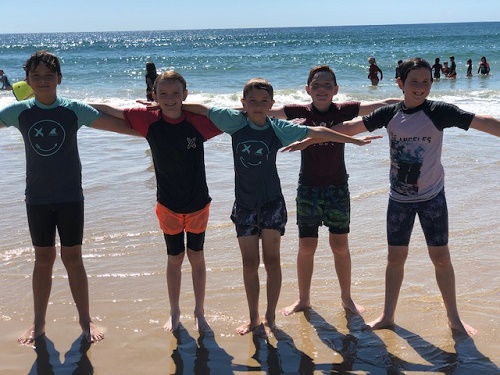 group of students smiling in the shallows at the beach